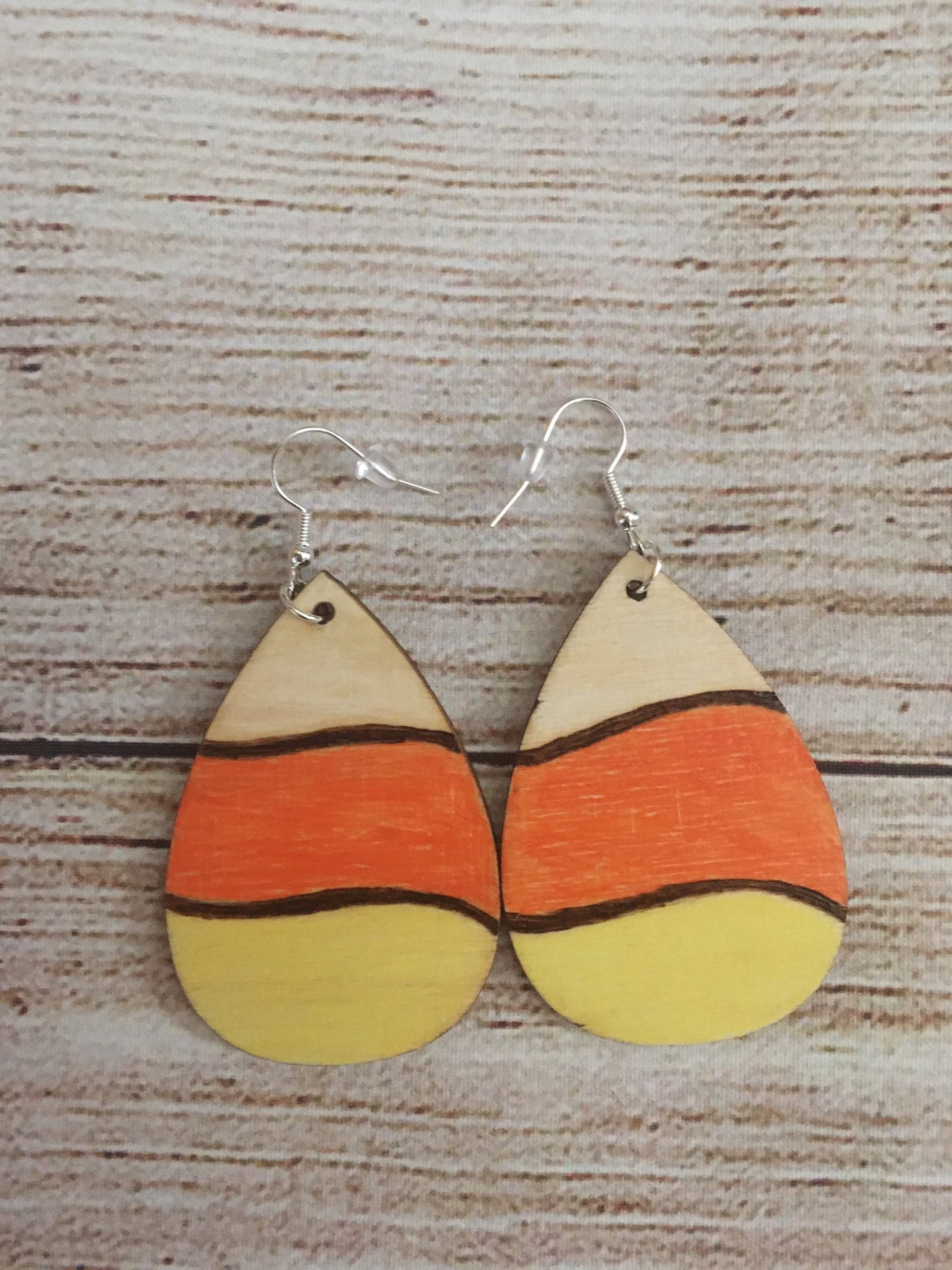 Wood burned earrings wood burned and colored like Halloween candy corn- white, orange, and yellow. Earrings have fishhooks and are teardrop shape.
