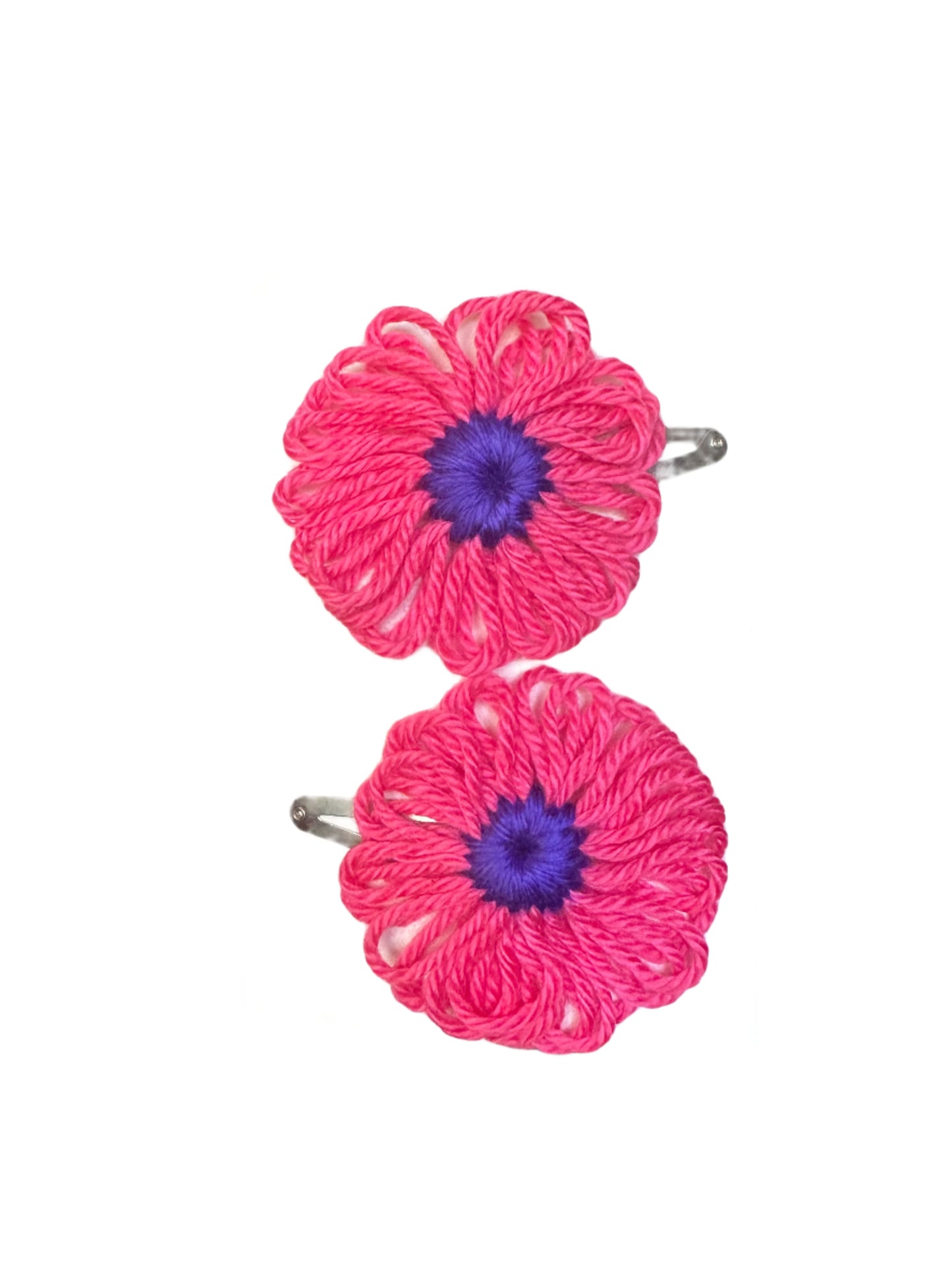 Two bright pink with purple centers yarn flowers snap clips with white centers on a gray surface