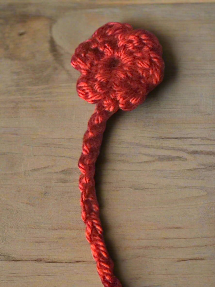 Red crocheted flower bookmark n a wooden background