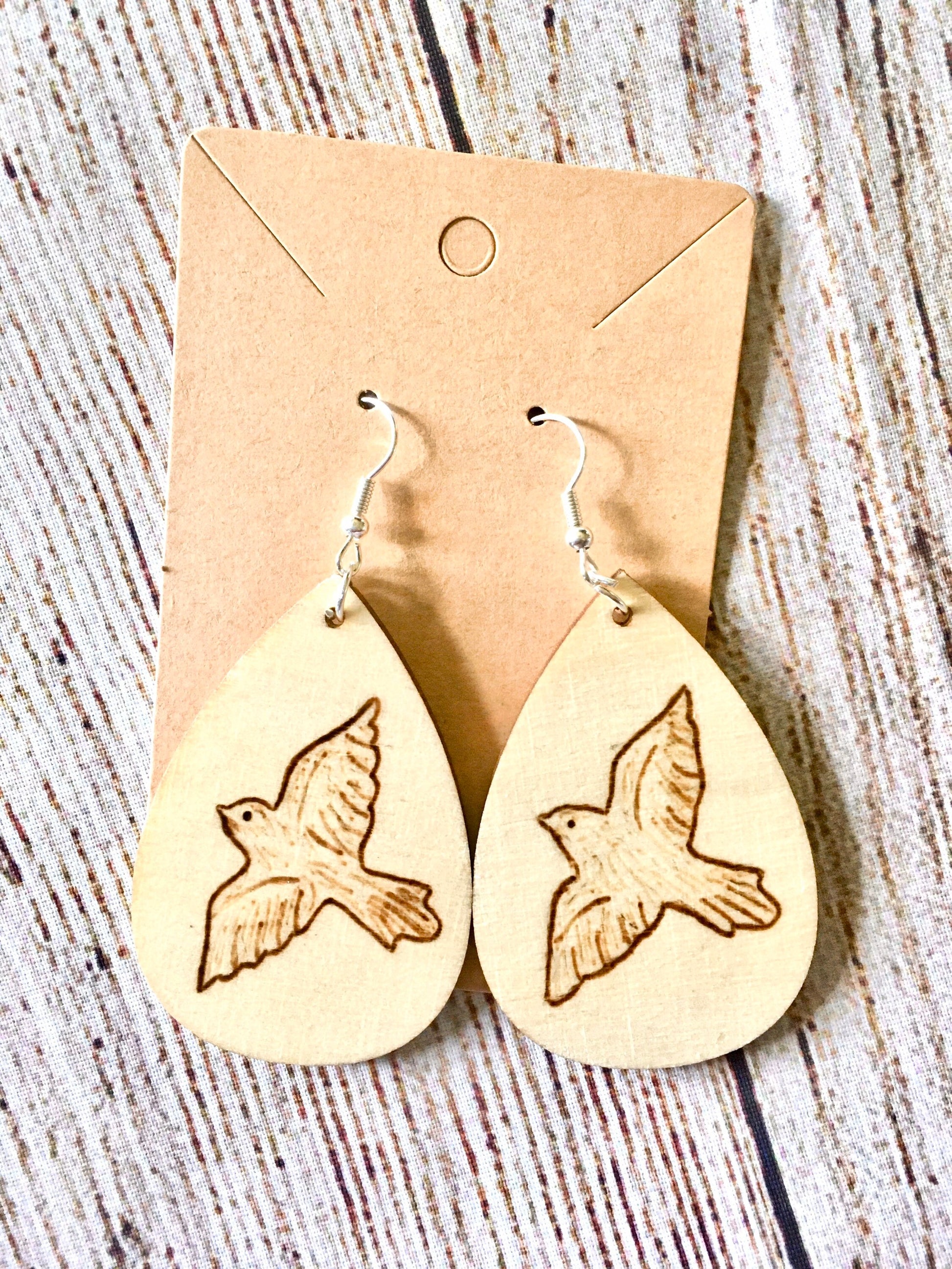 Wood burned earrings with dove bird  flying. Earrings are tear drop shaped with fishhooks.