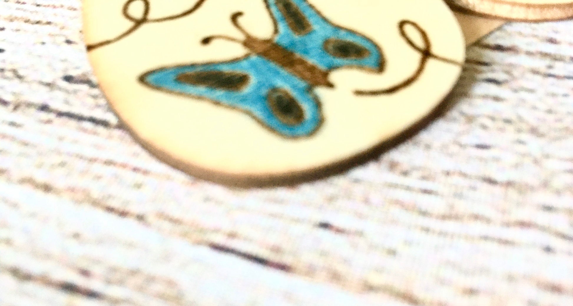 Wood burned earrings wood burned with butterflies colored blue.  Earrings have fishhooks and are teardrop shape.