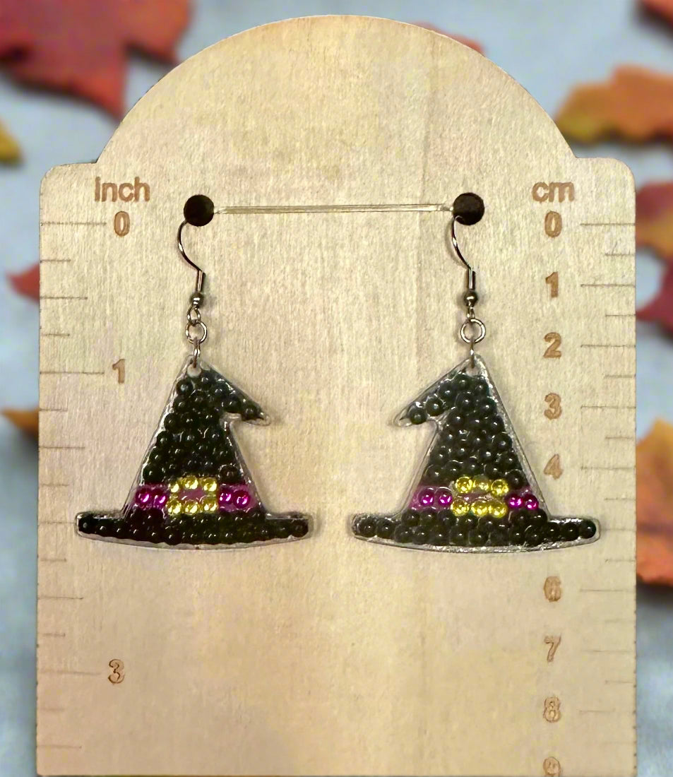 Witch hat earrings with colorful accents on a wooden display card with measurements.