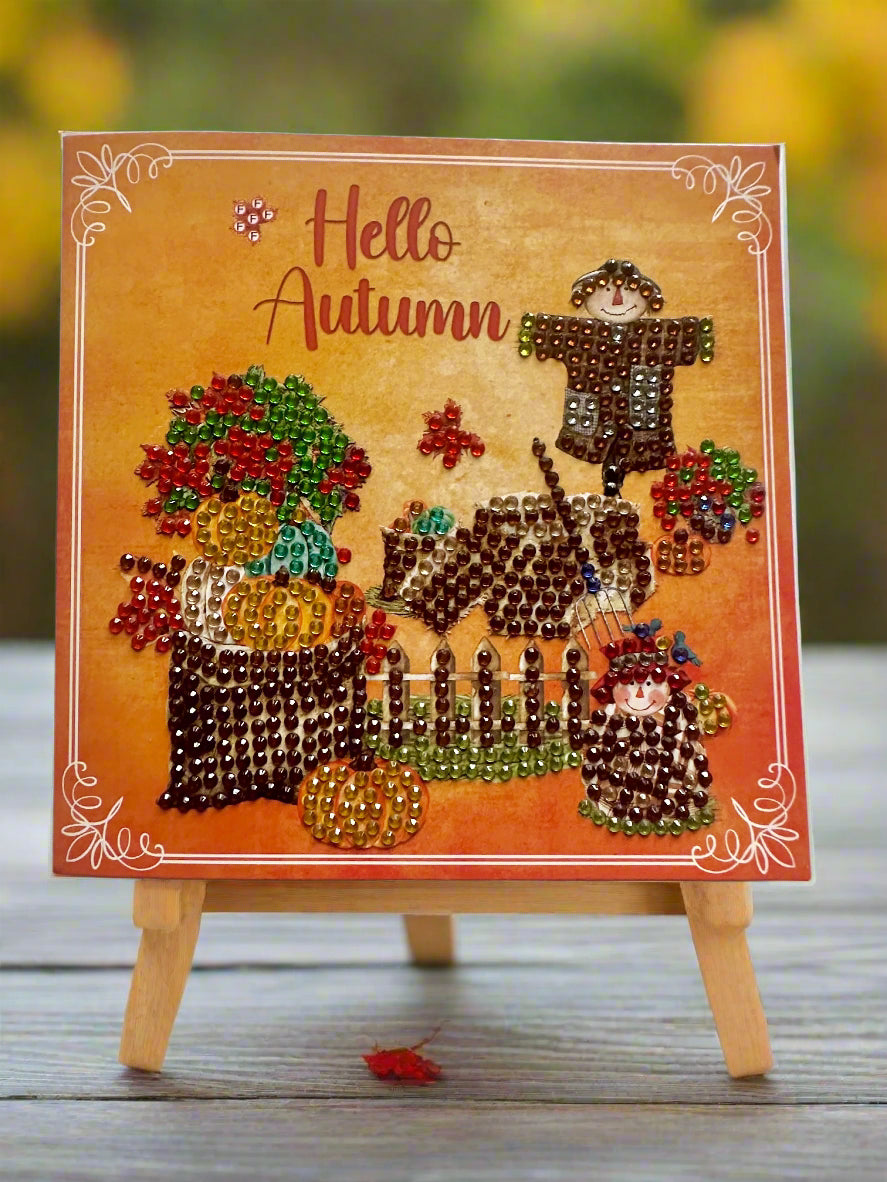 Autumn-themed diamond dot card on a stand, featuring text 'Hello Autumn' with scarecrows, pumpkins, and fall plants.