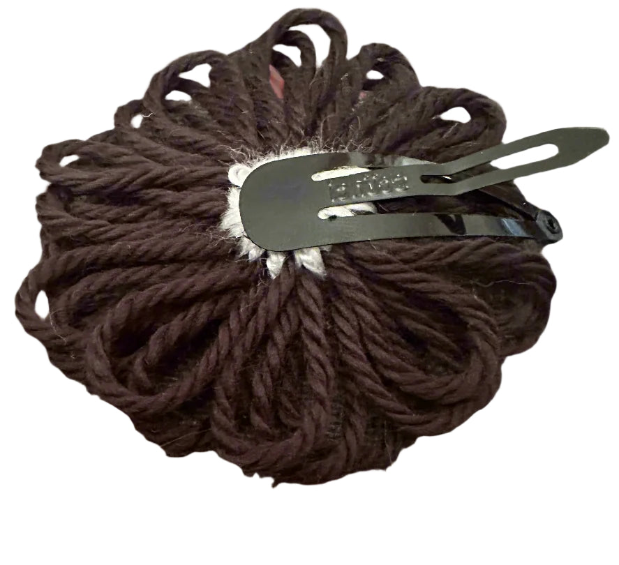 black with white yarn flowers snap clip on a gray surface with a metal clip on a white background