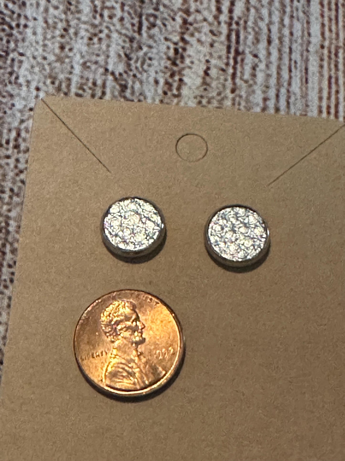 round stud earrings with a shiny silver faux leather center with penny to show size