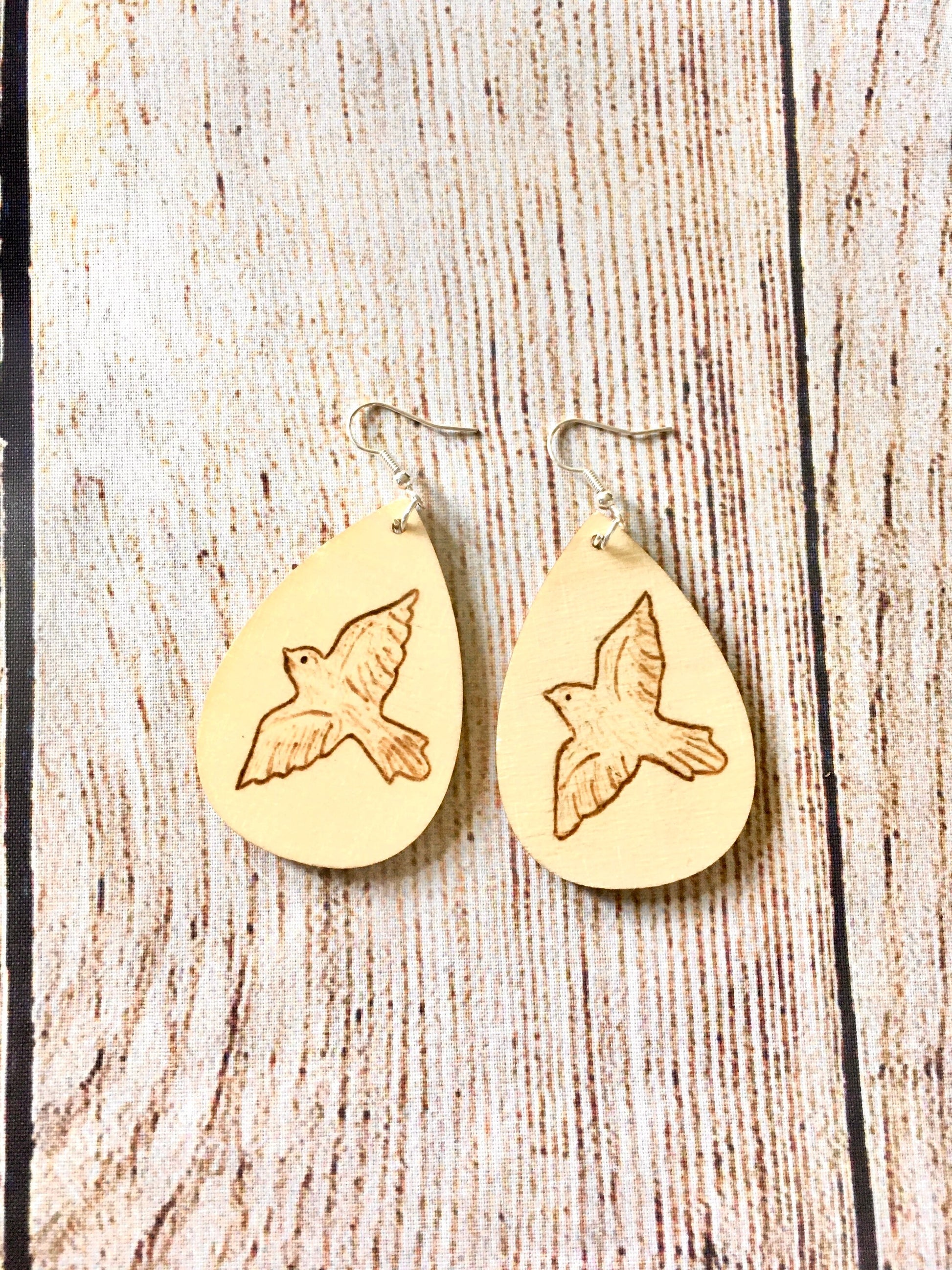Wood burned earrings with dove bird  flying. Earrings are tear drop shaped with fishhooks.