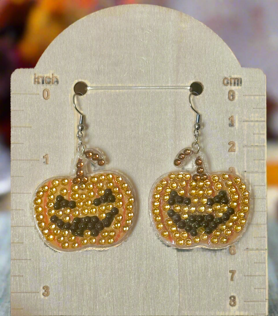 Pumpkin-shaped earrings with beaded design on a card with measurements