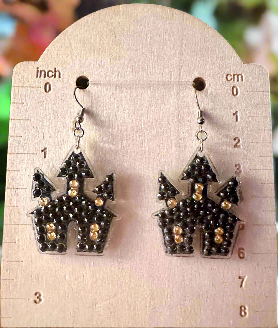 Halloween-themed castle earrings on a measuring card with inches and centimeters.