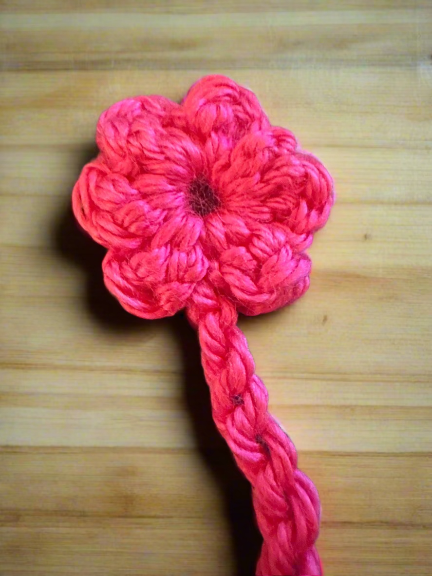 Pink crocheted flower on a wooden surface