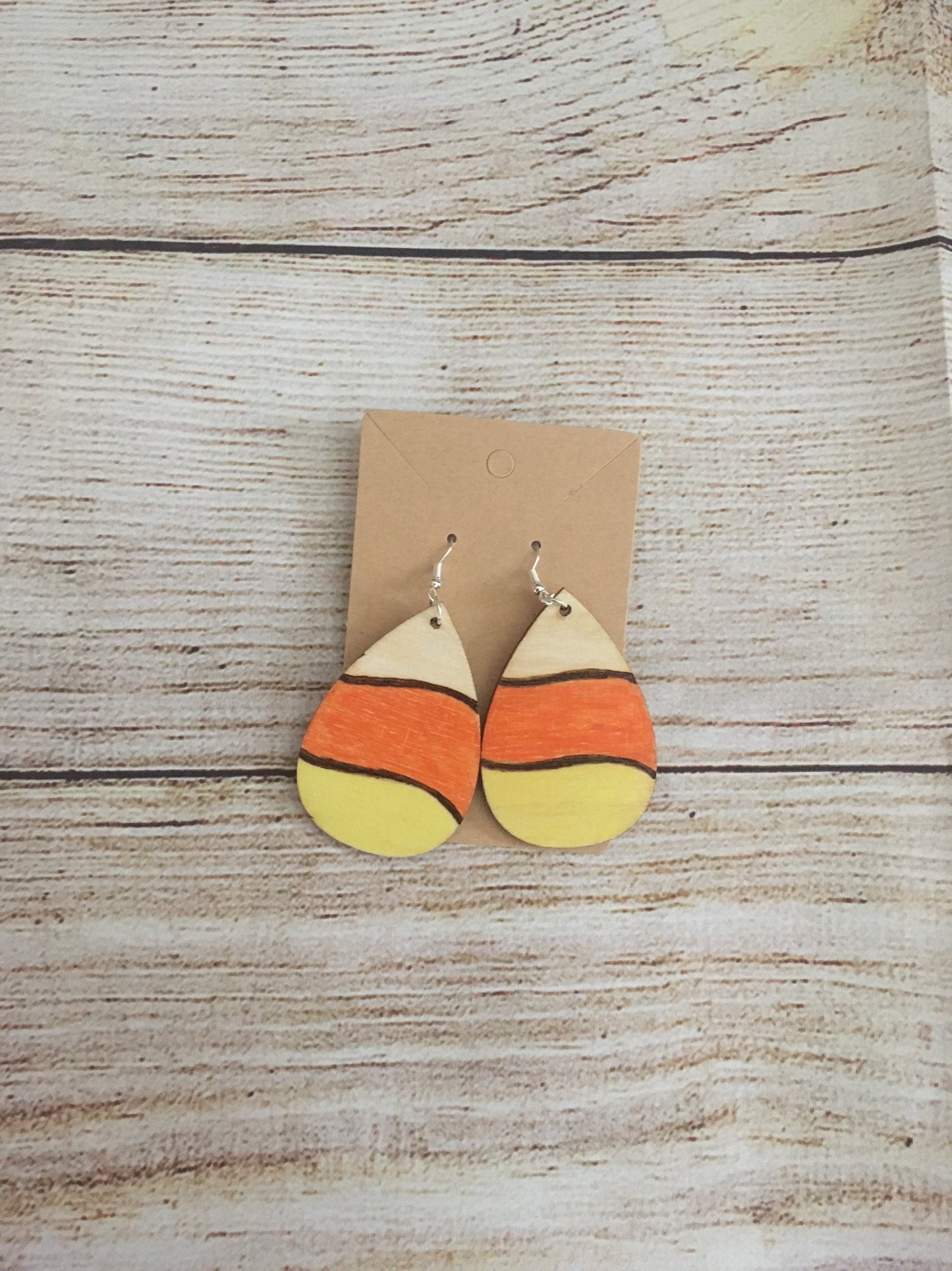 Wood burned earrings wood burned and colored like Halloween candy corn- white, orange, and yellow. Earrings have fishhooks and are teardrop shape.