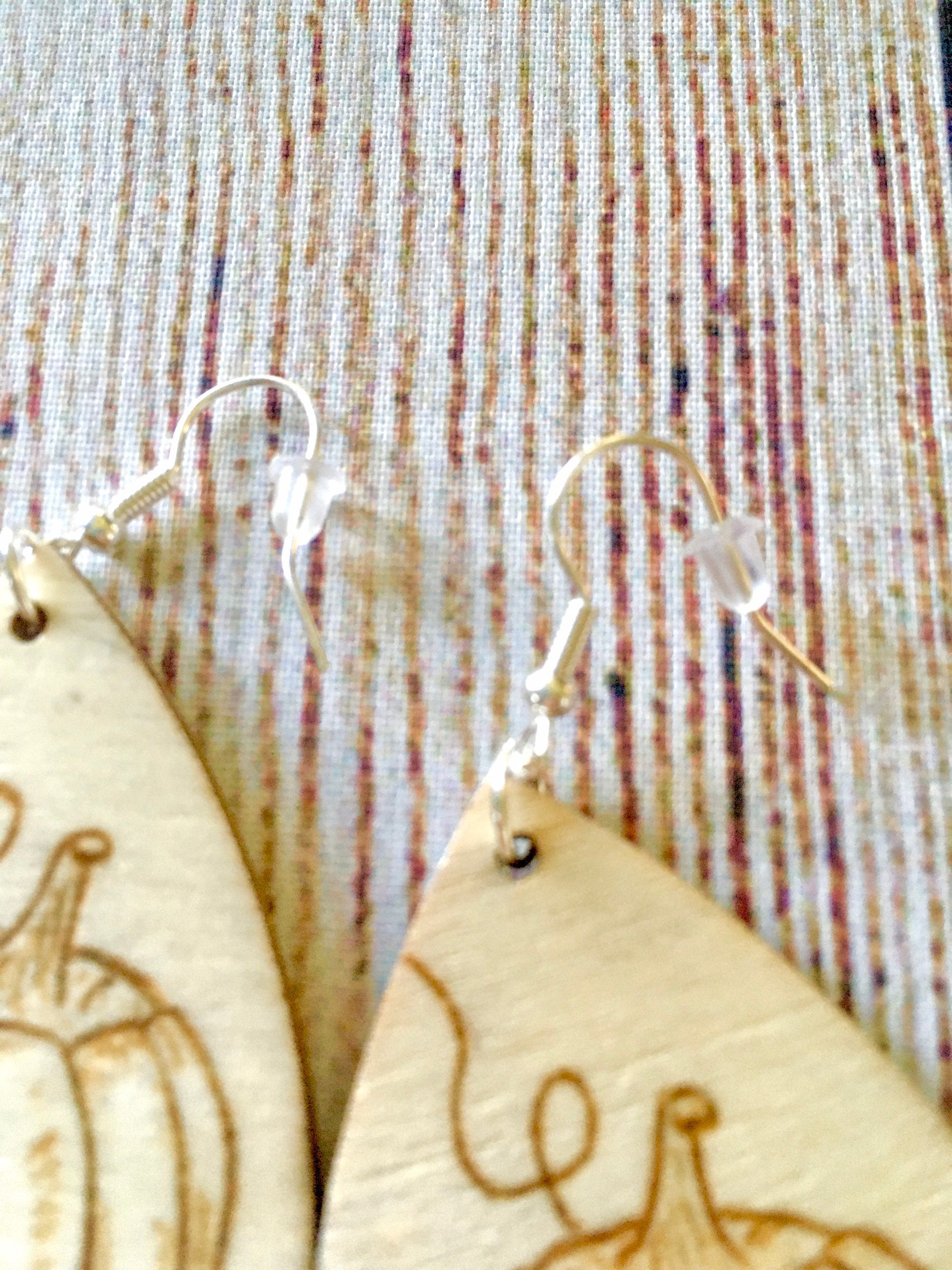Wood burned earrings with wood burned pumpkin sitting in the grass with leaves on the ground. Earrings are tear drop shaped with fishhooks.