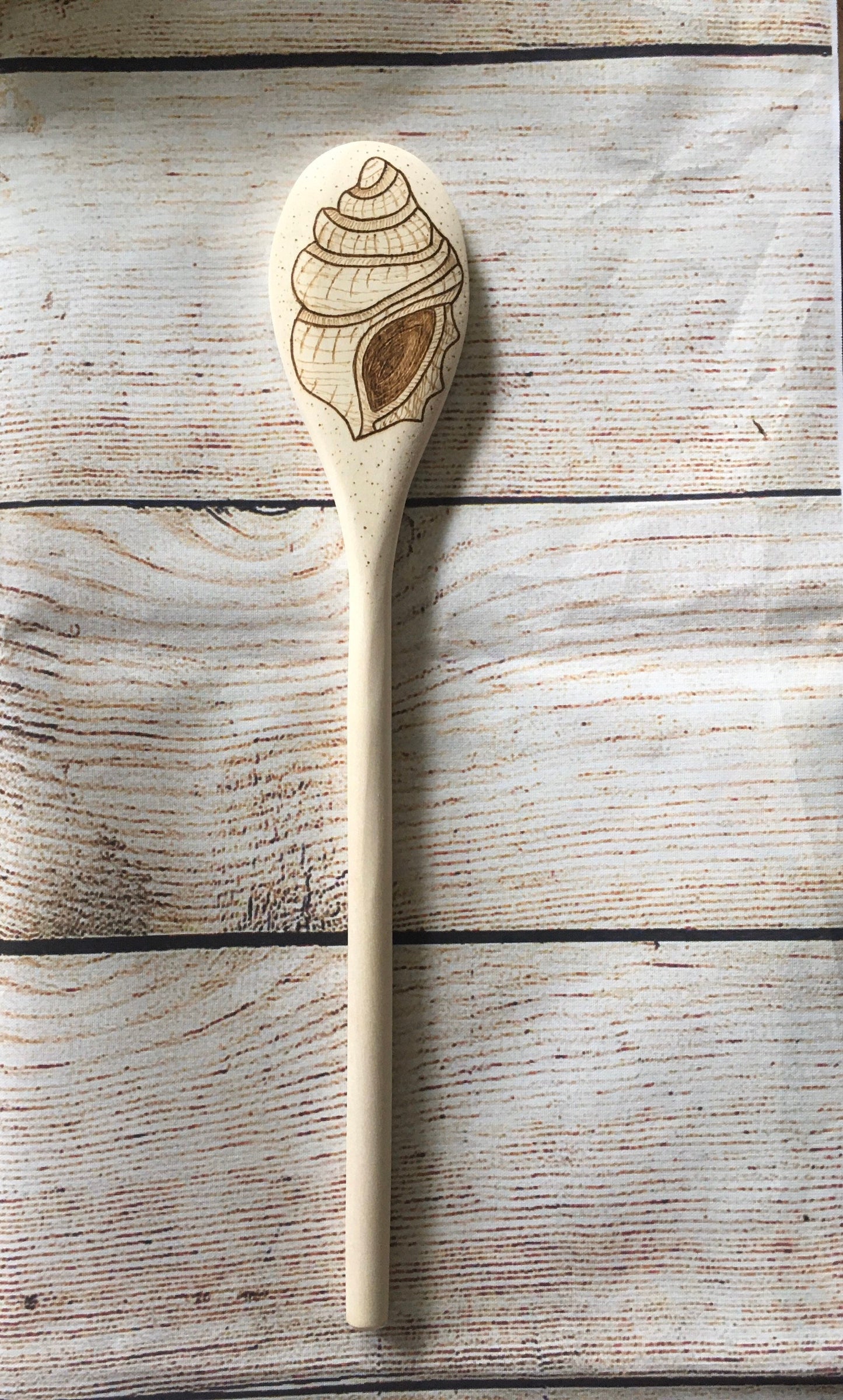 wood burned wooden spoon with a seashell burned on the back of the spoon