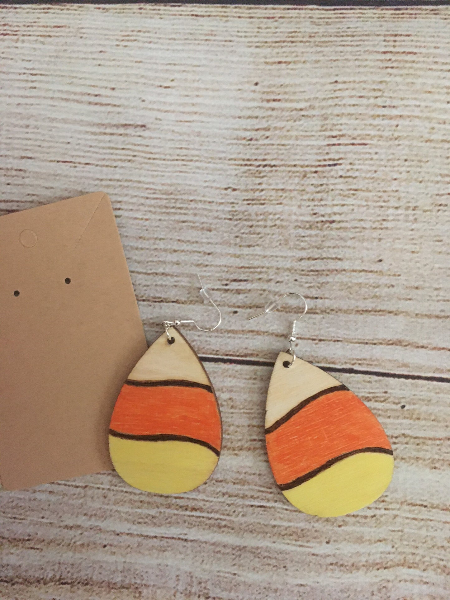 Wood burned earrings wood burned and colored like Halloween candy corn- white, orange, and yellow. Earrings have fishhooks and are teardrop shape.
