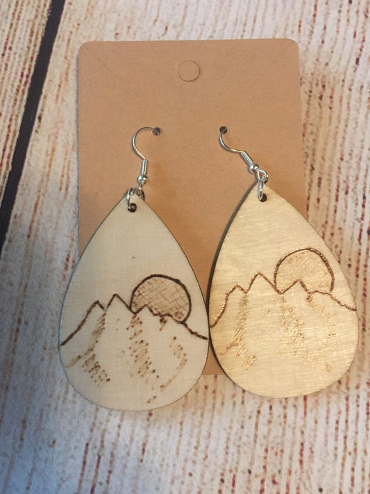 Wood burned earrings wood burned featuring a mountain and the sun or moon.  Earrings have fishhooks and are teardrop shape.