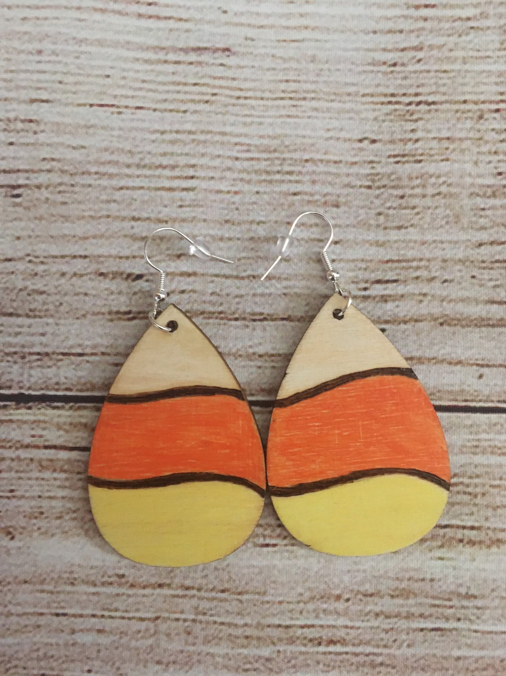 Wood burned earrings wood burned and colored like Halloween candy corn- white, orange, and yellow.  Earrings have fishhooks and are teardrop shape.