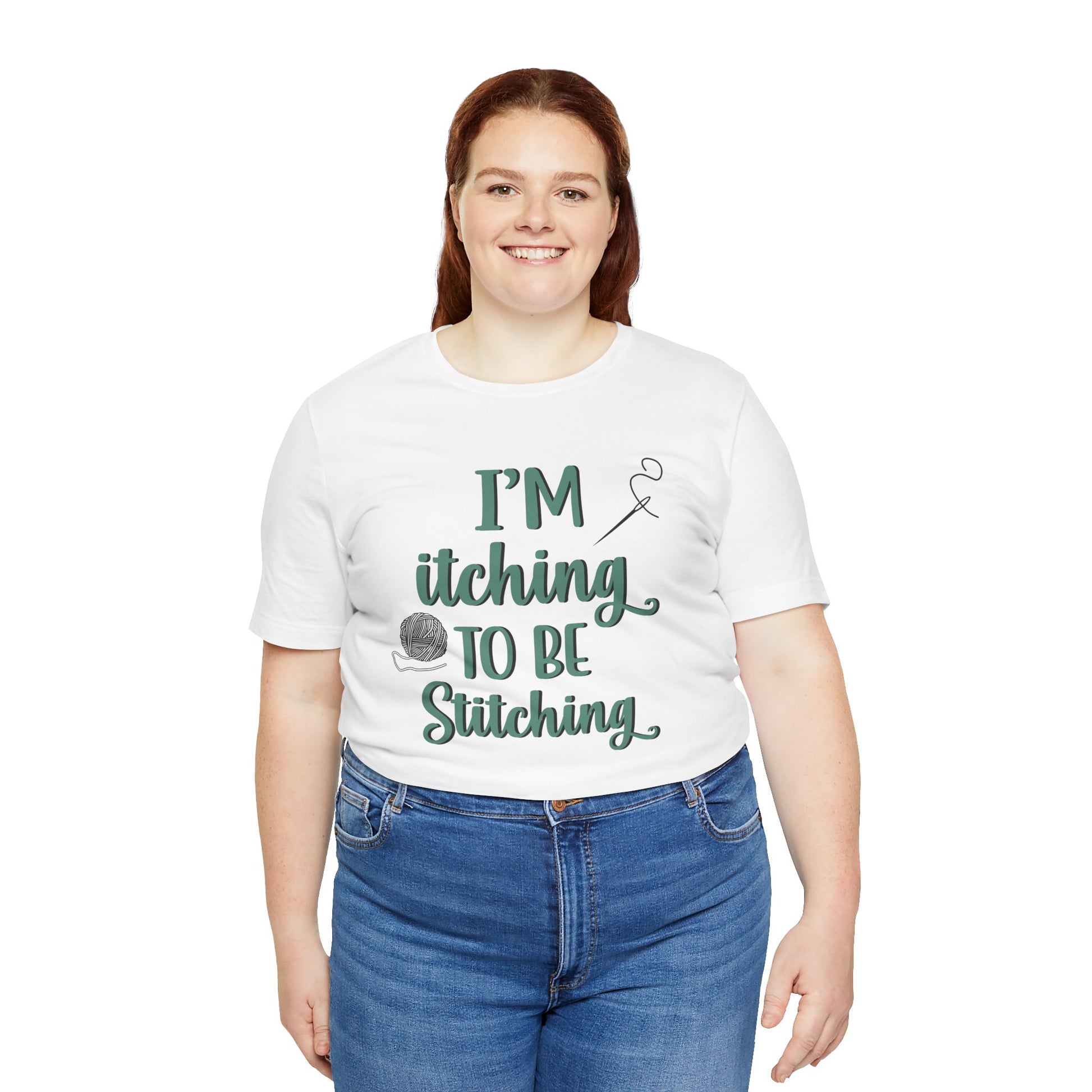 Funny Itching to be Stitching white colored T-Shirt with heather teal lettering, a ball of yarn, and a needle with thread worn by a woman