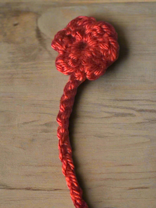 Red crocheted flower bookmark n a wooden background