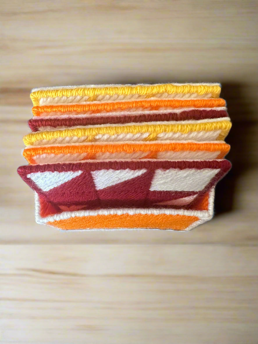 Stack of colorful maple leaf coasters on a wooden surface