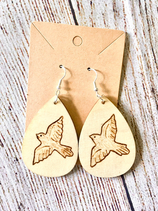 Wood burned earrings with dove bird  flying. Earrings are tear drop shaped with fishhooks.