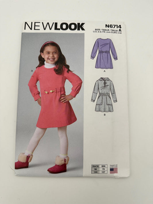 New Look sewing pattern packaging with a girl wearing a pink dress and patterned paper showing dress designs.
