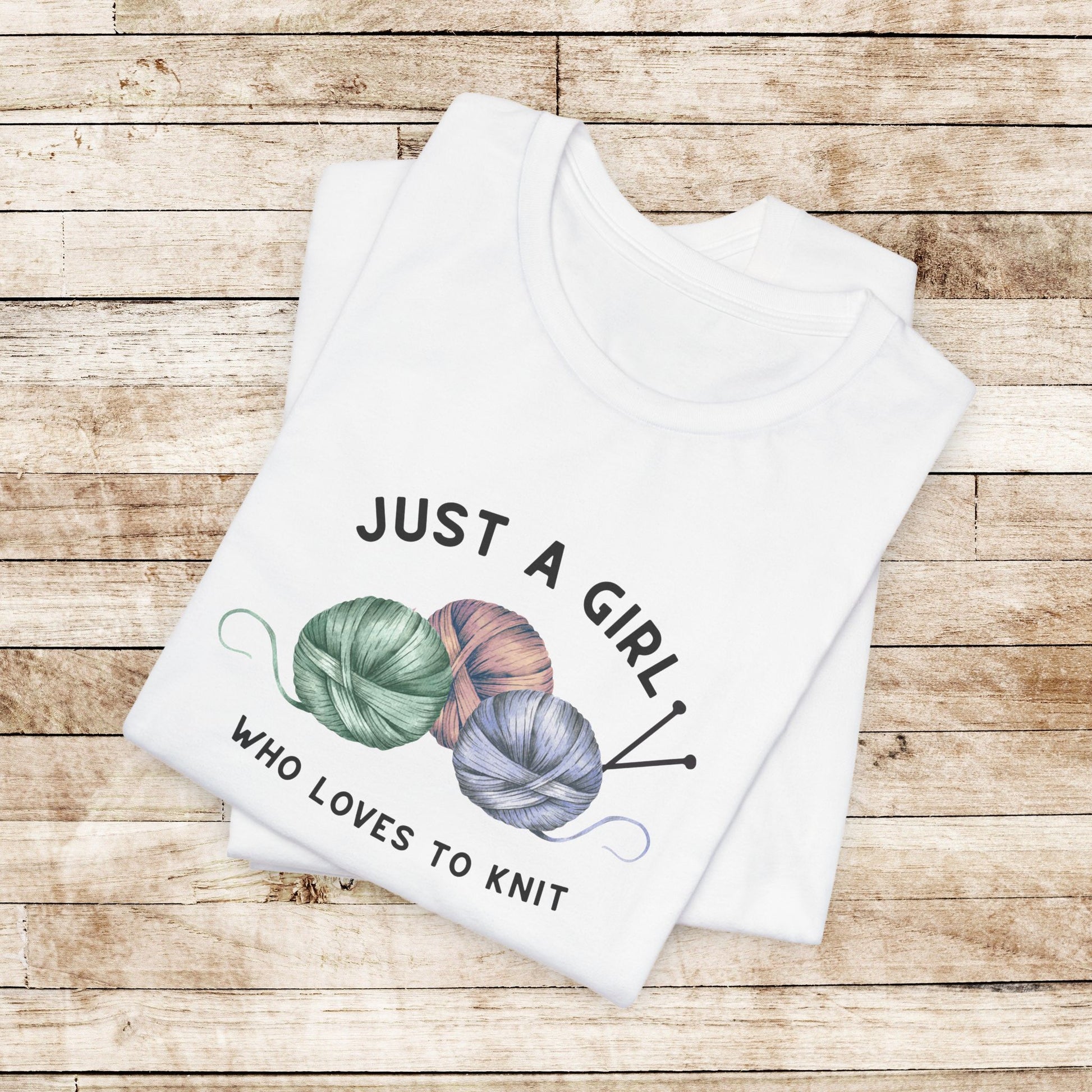 Funny Knitting T-Shirt- Just a Girl Who Loves to Knit, white folded shirt with black letters, 3 balls of yarn with knitting needles