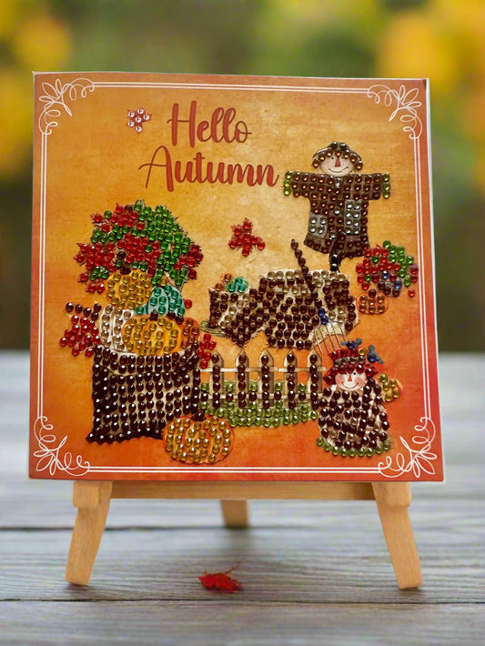 Autumn-themed diamond dot card on a stand, featuring text 'Hello Autumn' with scarecrows, pumpkins, and fall plants.