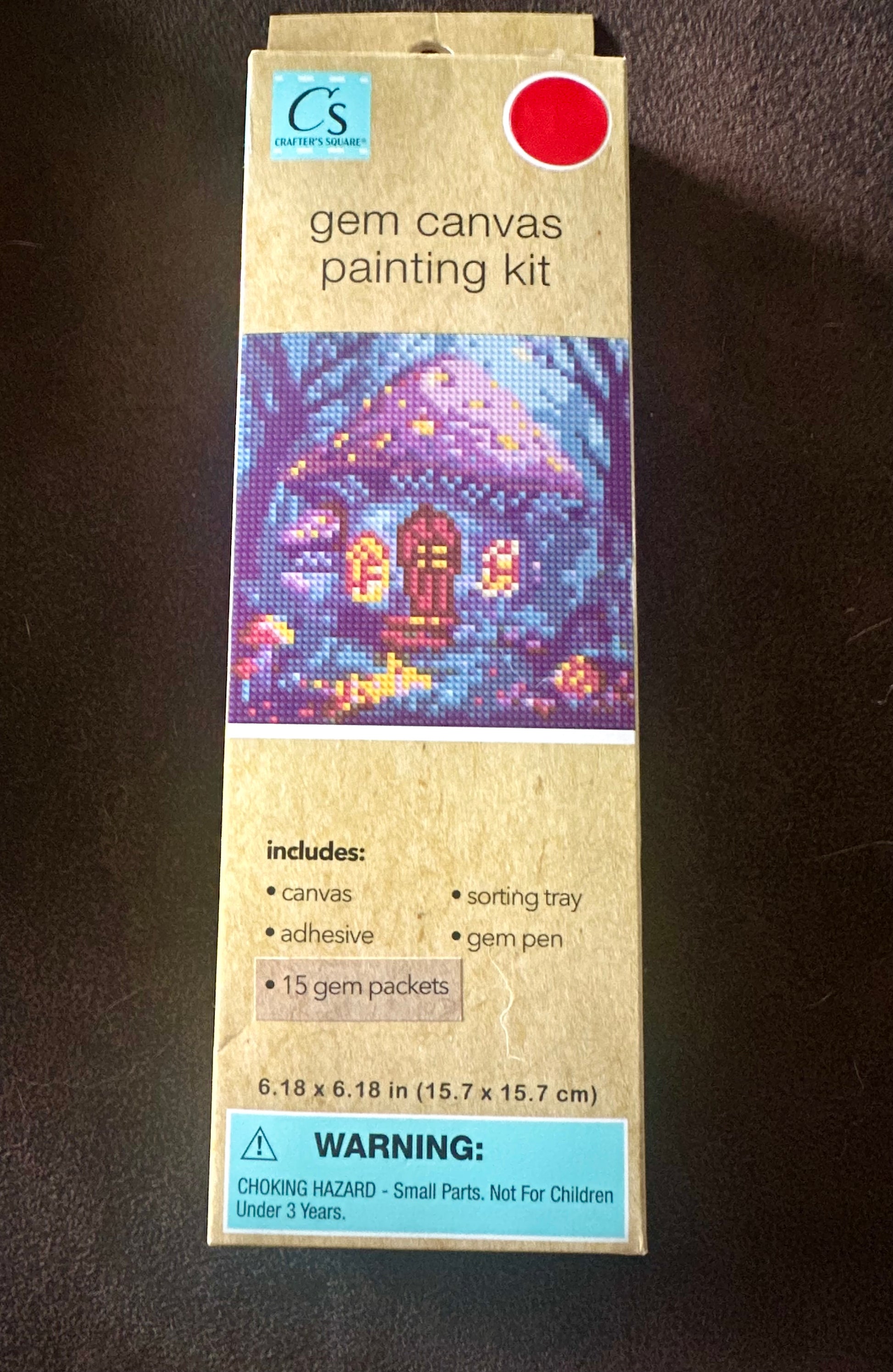 Box of gem canvas painting kit with a colorful mushroom house design on a blue colorful background with trees