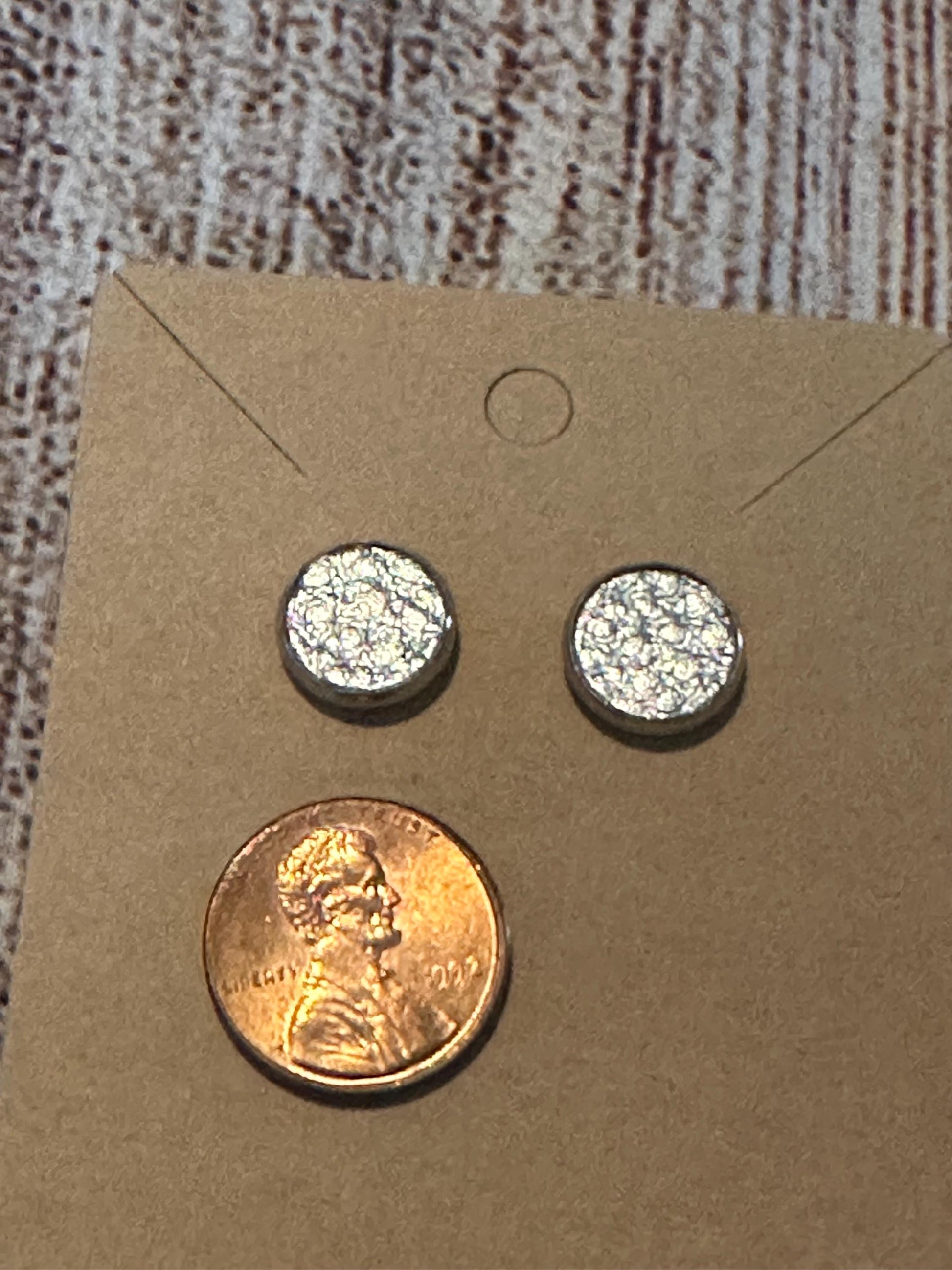 round stud earrings with a shiny silver faux leather center with penny to show size