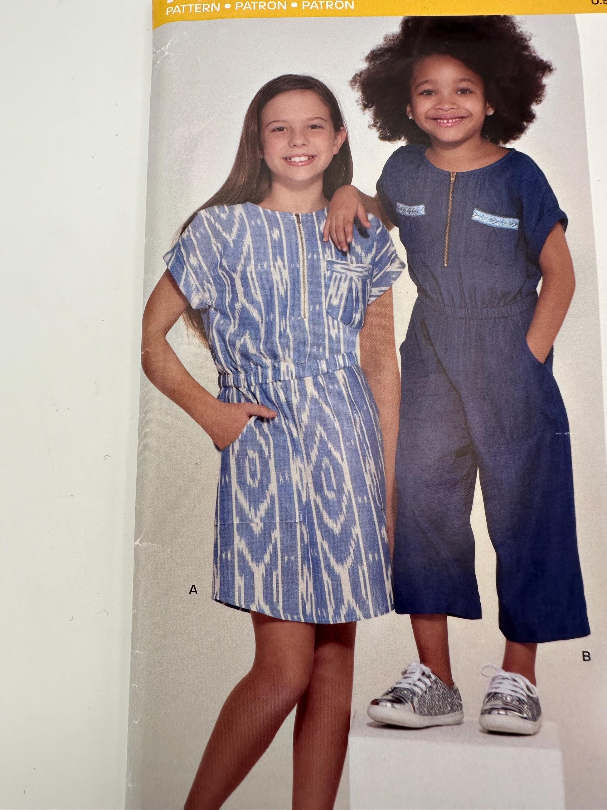 Two children wearing blue dresses on a pattern sheet.
