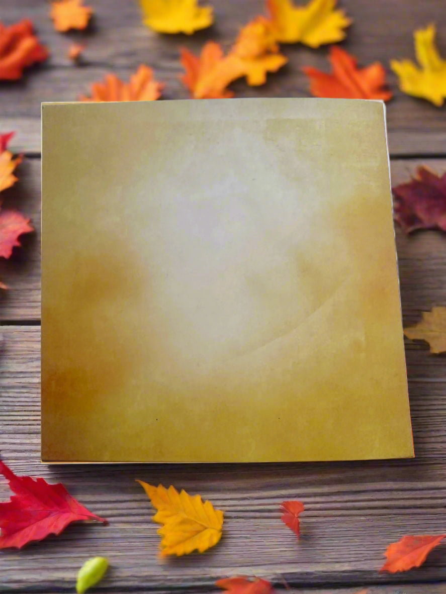 Back of 6x6 square fall card on a wooden surface with scattered autumn leaves.