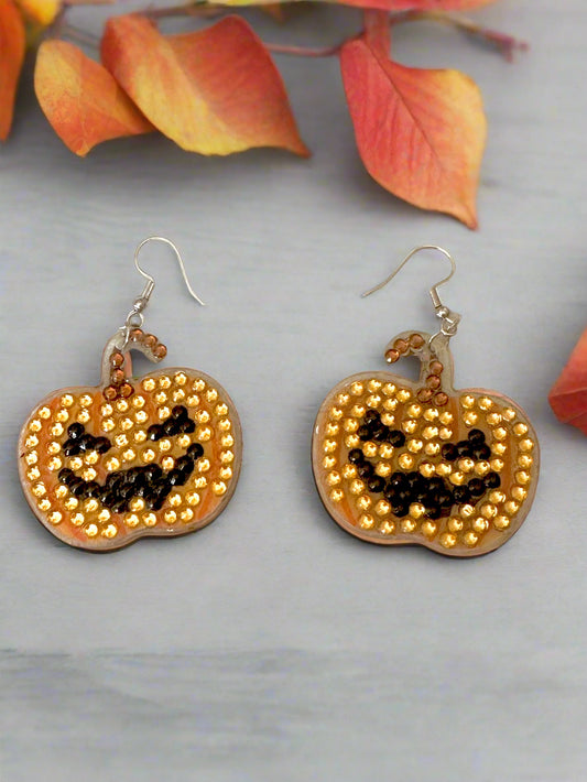 Pumpkin-shaped earrings with beaded design on a light background