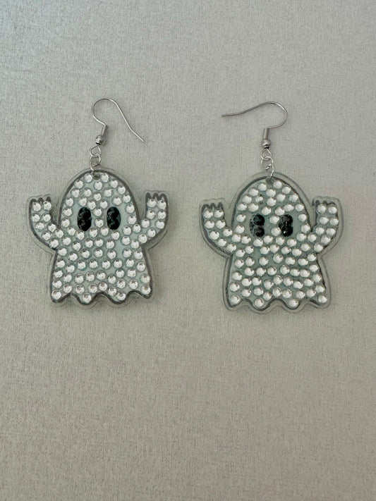 Ghost-shaped earrings with rhinestone detailing on a gray background