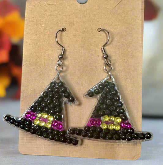 Witch hat earrings with black beads and colorful accents on a cardboard backing.