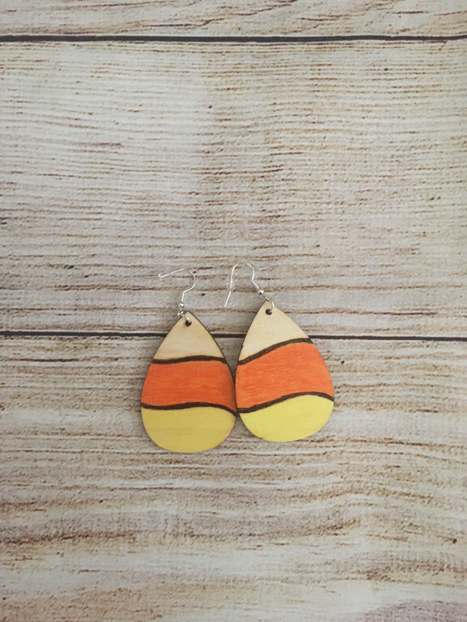 Wood burned earrings wood burned and colored like Halloween candy corn- white, orange, and yellow.  Earrings have fishhooks and are teardrop shape.