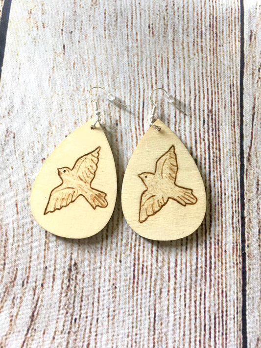 Wood burned earrings with dove bird  flying. Earrings are tear drop shaped with fishhooks.