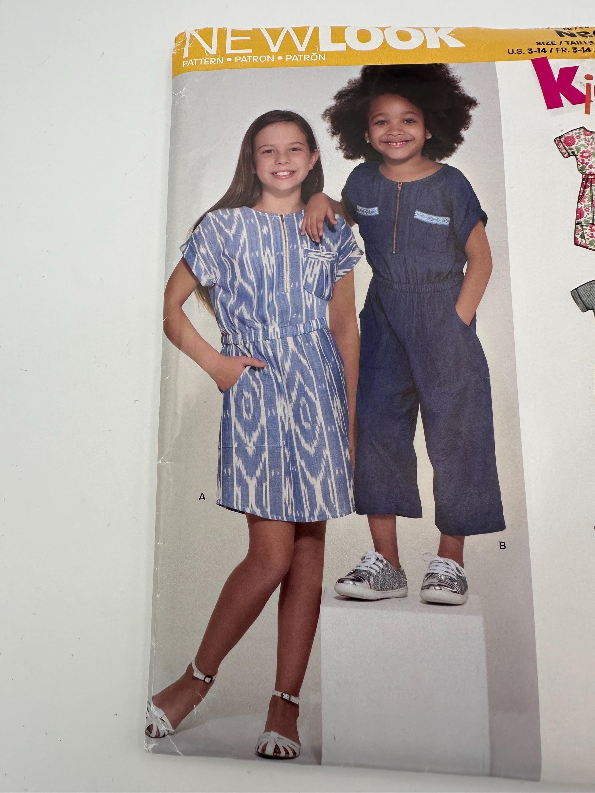 Pattern envelope for children's clothing with two models wearing a dress and jumpsuit.